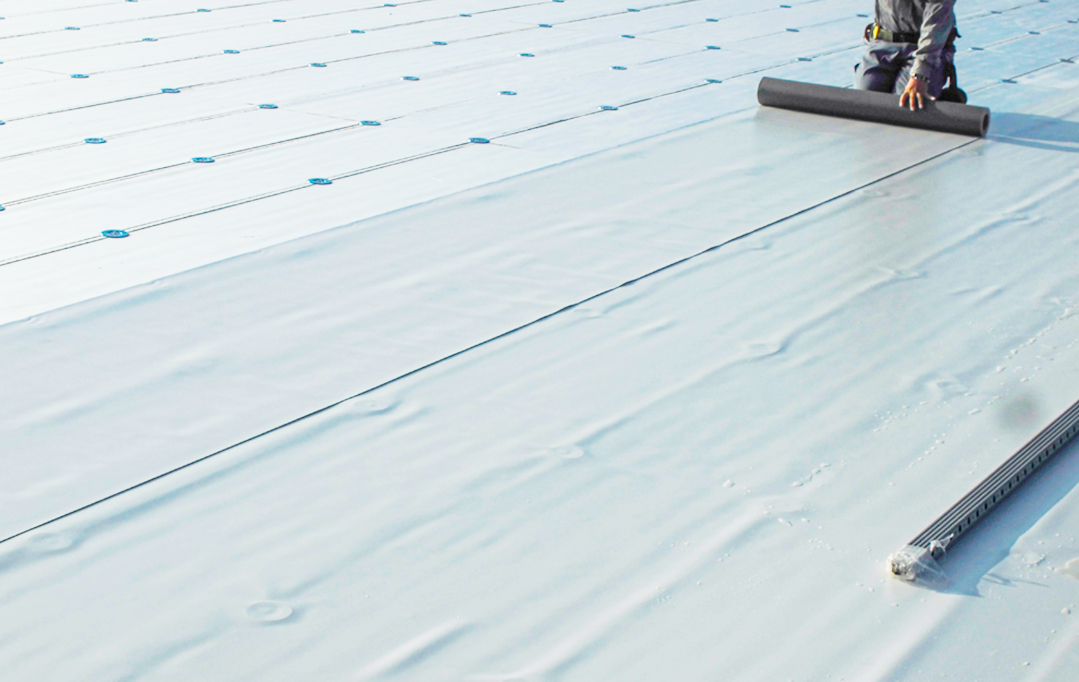 サーナルーフの防水シートを屋根に展開しながら施工している様子。